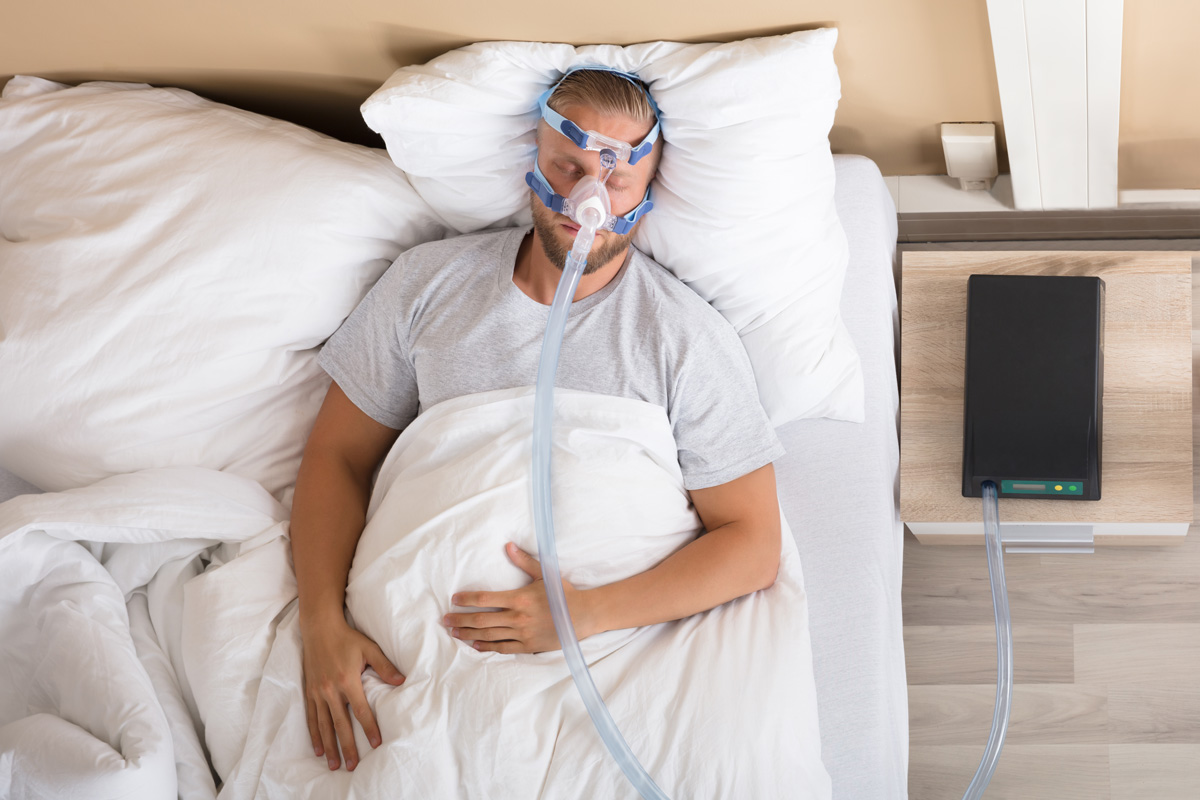 A man sleeping in bed while using a CPAP machine in El Paso.