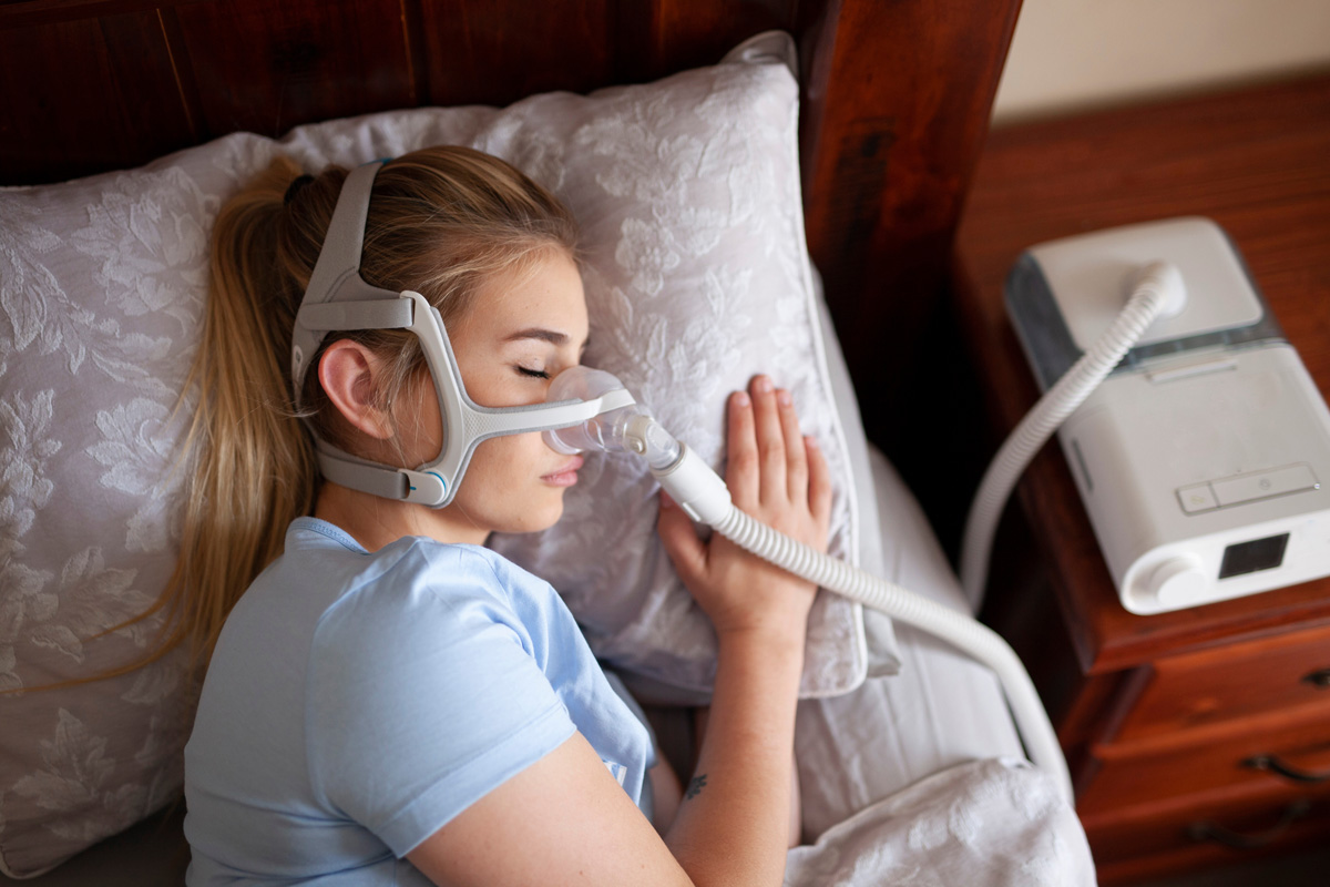 A woman laying in bed while using a CPAP machine in El Paso.