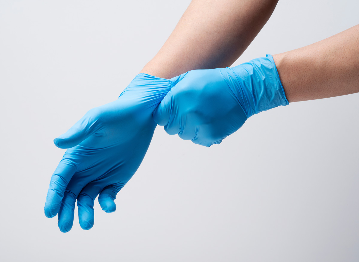 A person’s hands pulling on blue latex gloves in El Paso.